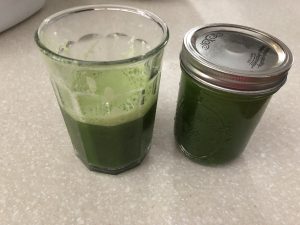 A glass and a small mason jar full of fresh green juice. This image is literally a picture of green juice made at home by Doctor Bijana. 